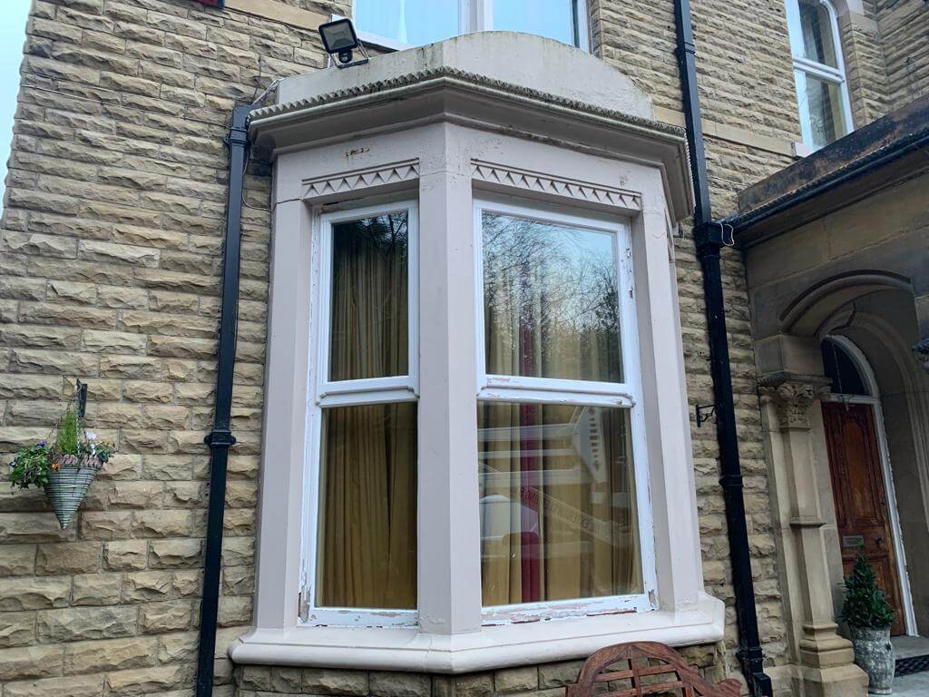 Before image of outer bay window covered in flaking paint and stained marks.
