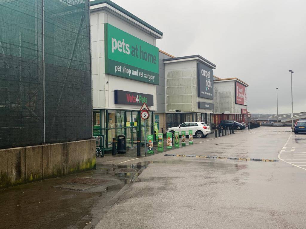 Before view of three large commercial shops in a row with stained and mossy outer walls.