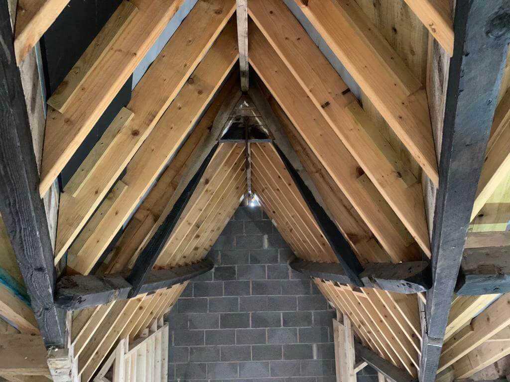 Before image showing interior loft wooden beams covered in black paint.