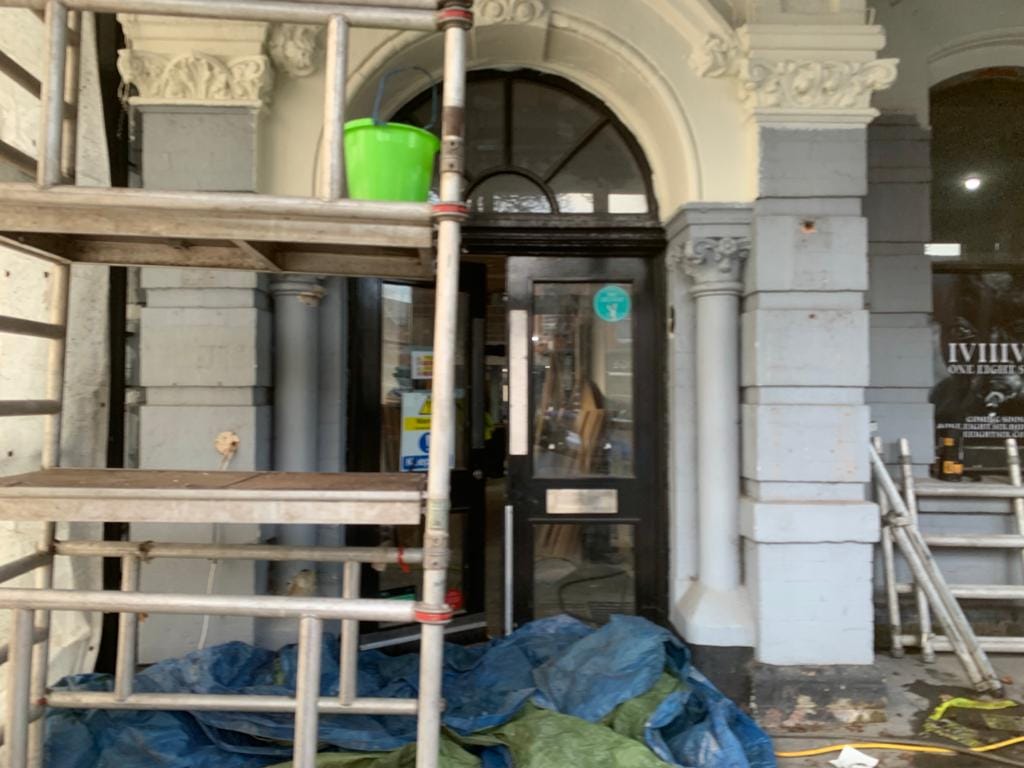 Before image of large commercial building entrance covered in flaking paint.