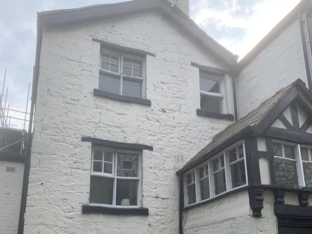 Before image of corner outer wall at pub with old flaking white paint.