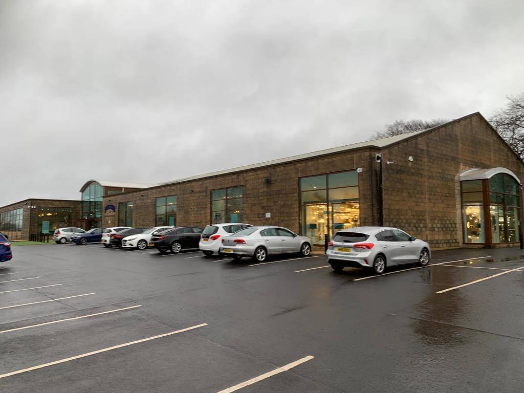 Wide angle before image of commercial property with stained and mossy brickwork across the whole building.