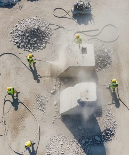 Overhead view of workers blasting concrete stumps on commercial site.